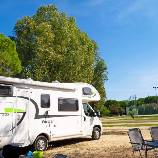 Wohnmobil mit Tischen und Stühlen vor dem Sportplatz des Camping Cala Ginepro